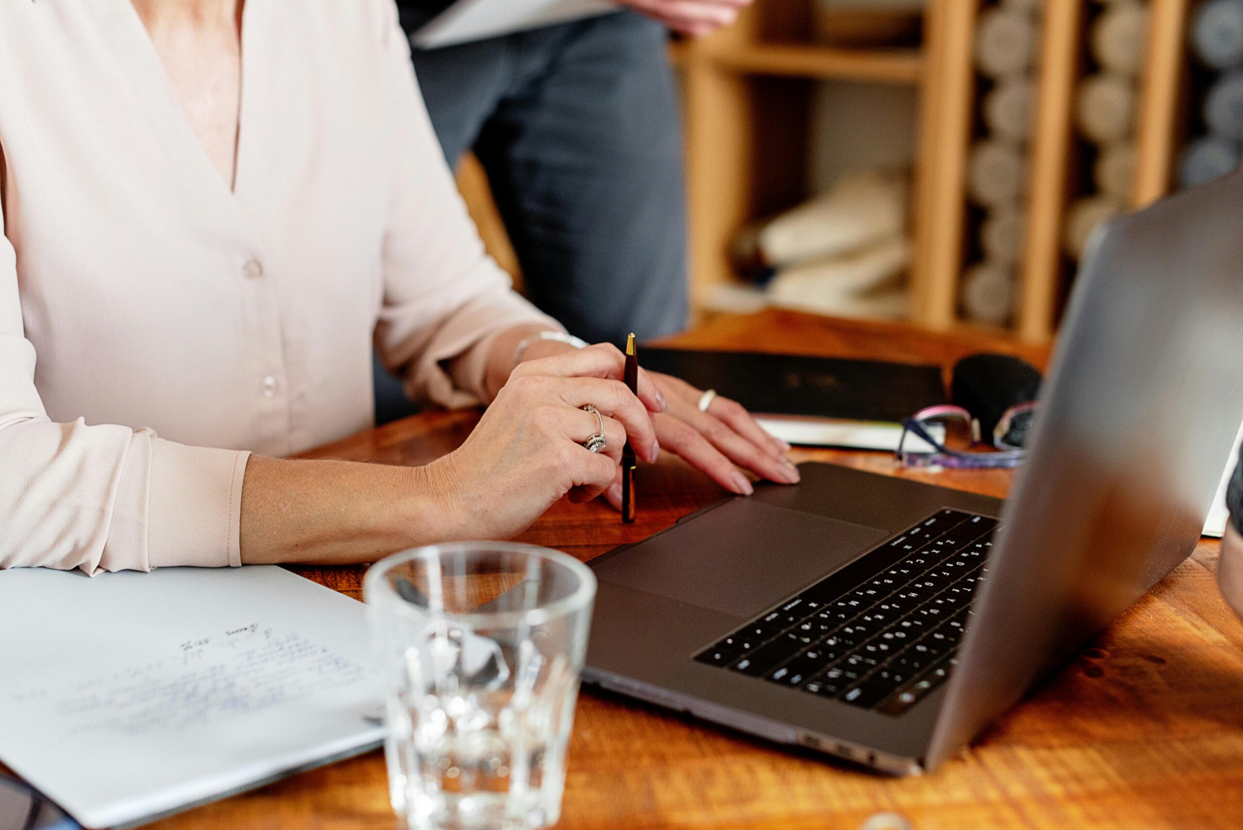 woman writing at computer with pen and notebook editing ai draft